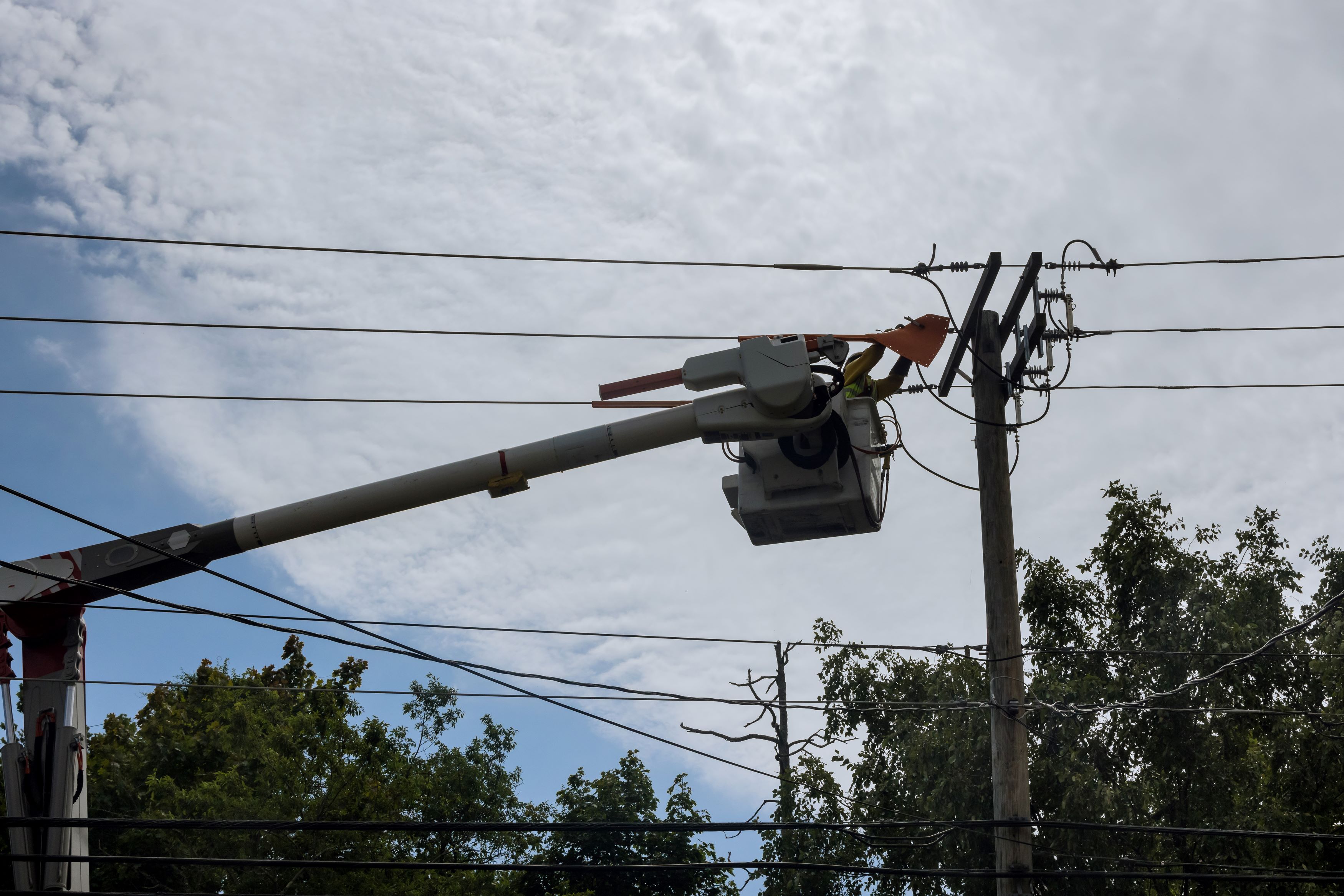 Bucket truck positioning a new utility pole for placement